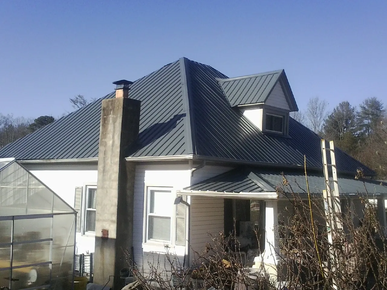 Dark blue standing seam metal roof on a white farmhouse with dormer — Slate & Tile Roof Repair by Roofing Brothers in Fairmount