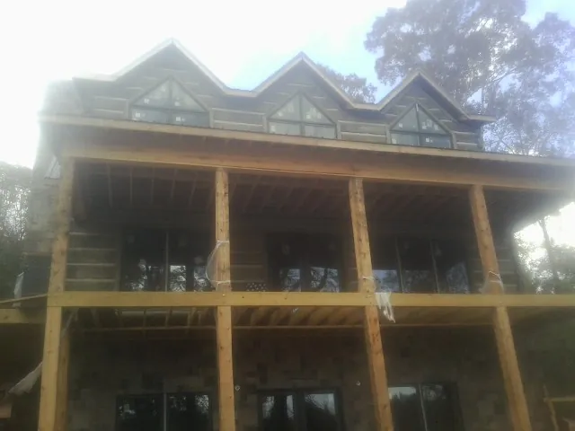 Dormers and porch framing on a large log home under construction — Roof Coating work by our crew in Fairmount